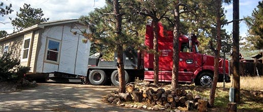 Red truck moving mobile home to a new lot