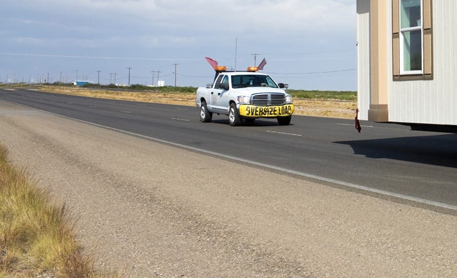 pilot car driving being truck with large load carrying mobile home